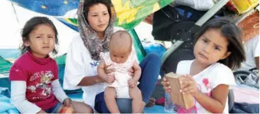  ?? Reuters ?? ↑
An Afghan family sits outside a tent in the Community Center managed by Team Humanity in Lesbos on Saturday.