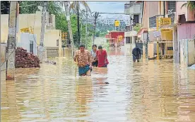  ?? PTI ?? Residents wade through a waterlogge­d street after heavy overnight rain, in Bengaluru.