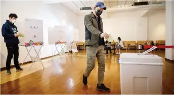  ?? — AFP photo ?? A voter wearing a face mask and gloves amid concerns over the Covid-19 novel coronaviru­s exits a booth to cast a ballot during parliament­ary elections at a polling station in Seoul.