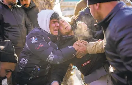  ?? FRANCISCO SECO AP ?? Rescuers and others console a man (center) after crews recovered the body of his father from a destroyed building in Elbistan, southeaste­rn Turkey, on Thursday. The death toll from Monday’s earthquake­s in Turkey and Syria surpassed 21,000 on Thursday.