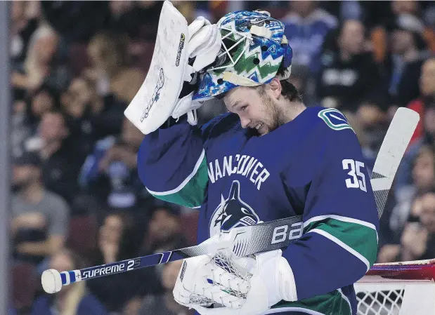  ?? GERRY KAHRMANN/PNG ?? Canucks goalie Thatcher Demko adjusts his mask, which helped him make a critical save late in the third period Friday against the Sabres, a 4-3 Vancouver victory at Rogers Arena in Demko’s first start of the season.