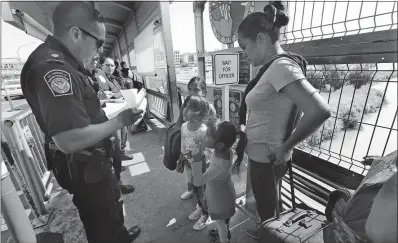  ?? [MARCO UGARTE/THE ASSOCIATED PRESS] ?? A U.S. Customs and Border Protection officer checks the documents of migrants as they cross into the United States from Nuevo Laredo, Mexico, on Wednesday. Asylum-seekers are grappling to understand what a new U.S. policy that all but eliminates refugee claims by Central Americans means.