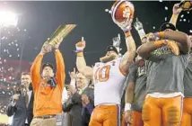  ?? LOREN ELLIOT/TNS ?? Clemson head coach Dabo Swinney holds the College Football Playoff National Championsh­ip trophy while his team celebrates Monday.