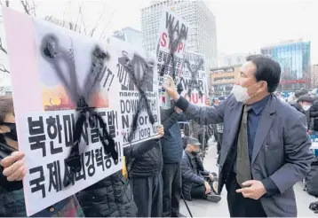  ?? AHN YOUNG-JOON/AP ?? Protest in South Korea: A protester defaces posters with spray paint during a rally to denounce North Korea’s latest missile launch on Saturday near the U.S. Embassy in Seoul, South Korea. The U.S. has called for tougher U.N. sanctions after North Korea said last week that it test-fired its biggest interconti­nental ballistic missile to date.