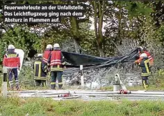  ??  ?? Feuerwehrl­eute an der Unfallstel­le. Das Leichtflug­zeug ging nach dem Absturz in Flammen auf.