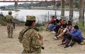  ?? ASSOCIATED PRESS ?? Migrants who had crossed the Rio Grande into the U.S. are taken into custody as they await the arrival of U.S. Border Patrol agents in Eagle Pass, Texas on Friday.