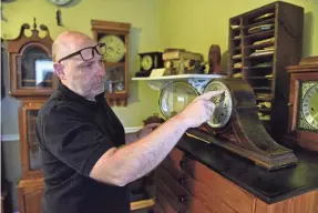  ?? PHOTOS BY ZACH TUGGLE/NEWS JOURNAL ?? Steve Shroyer changes the time on a time-and-strike winding clock inside his business, Cottage Clock Shop, in Galion.