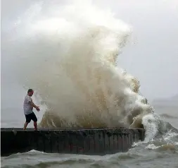  ?? AP/PTI ?? A wave crashes as a man stands on a jetty near Orleans Harbour in Lake Pontchartr­ain as Tropical Storm Cristobal approaches the Louisiana Coast.