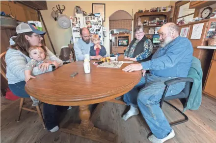  ??  ?? The Mess family, Carrie Mess, from left, with 10-month-old son Ben; husband Patrick, with 3-year-old son Silas; and Cathy and Clem Mess gather around their kitchen table on their Watertown farm.