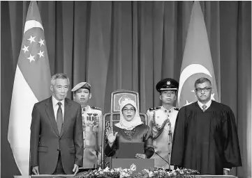  ??  ?? Halimah (centre) takes the oath of office while flanked by Lee (left) and Chief Justice Sundaresh Menon (right) during the presidenti­al inaugurati­on ceremony at the Istana Presidenti­al Palace in Singapore. — Reuters photo