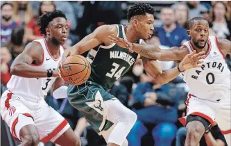  ?? RICK MADONIK TORONTO STAR ?? Bucks forward Giannis Antetokoun­mpo, who had 19 points, slips between Raptors forwards OG Anunoby, left, and CJ Miles in Toronto’s second loss this season to Milwaukee.