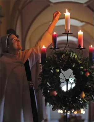  ?? By Valerie O’Sullivan ?? Sr Angela lights the fifth candle at first Vespers of Christmas. The symbolism of light goes back to the pre-Christian winter solstice festival, the date on which the sun, at its weakest, begins to revive and grow stronger and brighter.Photos