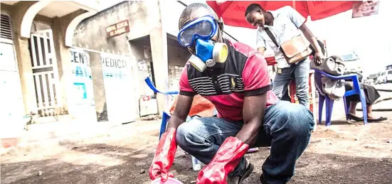  ??  ?? A HEALTH worker wearing protective gear mixes water and chlorine in Goma, DR Congo.