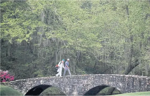  ?? REUTERS ?? Tiger Woods and his caddie walk over the Nelson Bridge at Augusta National during the 2019 Masters.