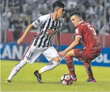  ?? FOTO: AFP ?? Jesús Medina, del Libertad, conduce el balón pegado al pie ante el argentino Fernando Cosciuc. Los paraguayos fueron superiores.