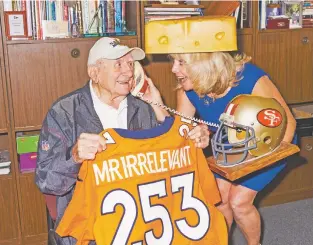  ?? JAKE MICHAELS/THE NEW YORK TIMES ?? Paul Salata holds a Mr. Irrelevant jersey next to his daughter, Melanie Fitch, on April 24 in Newport Beach, Calif. Salata, a 90-year-old former profession­al football player with a charitable streak and mischievou­s sense of humor, conceived the...