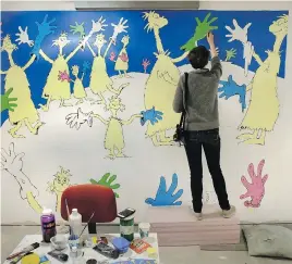  ??  ?? Cortney Thibodeau, a senior at University of Massachuse­tts at Amherst, paints a mural based on the artwork of Dr. Seuss.