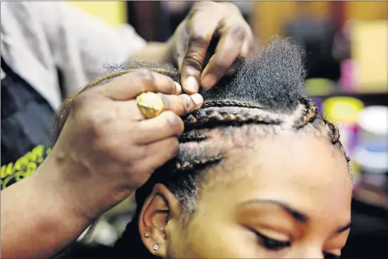  ?? [COURTNEY HERGESHEIM­ER/DISPATCH] ?? Naba Ba, originally from Senegal, braids cornrows in Ashauna Mathews’ hair at Queen Bee’s Royal Hair Gallery earlier this year. Thanks to changes in state law, Ba can practice braiding without going through hundreds of hours of training.