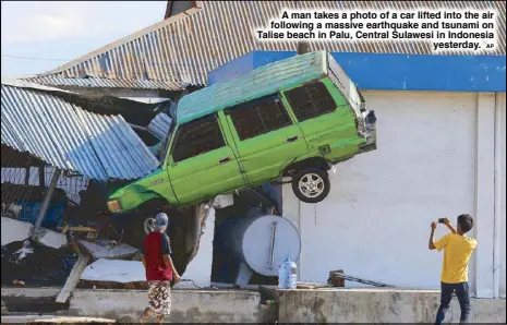  ??  ?? A man takes a photo of a car lifted into the air following a massive earthquake and tsunami on Talise beach in Palu, Central Sulawesi in Indonesia yesterday.