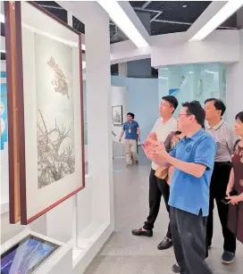  ??  ?? Artist Tang Qing explains one of his animal paintings to visitors.