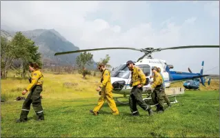  ?? Herald photo by Ian Martens ?? Members of the initial attack fire crew walk from a helicopter after loading gear Friday in Waterton after Parks Canada issued an evacuation alert with a wildfire burning in the Boundary Creek Valley in Glacier National Park south of the Waterton townsite. After substantia­l rainfall Monday, the evacuation alert was lifted. @IMartensHe­rald