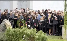  ??  ?? Family members, friends and musicians lay flowers graveside at funeral services for Cornell at Hollywood Forever Cemetery on Friday. (Below) Fans mourn at the graveside; (Far left) Vicky Cornell, Cornell’s widow, with children Lillian Jean Cornell,Toni...