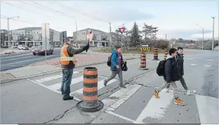  ?? DAVID BEBEE WATERLOO REGION RECORD ?? Crossing guard Rick Spurgeon stops traffic for students crossing the Fischer-Hallman Road roundabout at Seabrook Drive in Kitchener.