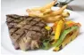  ??  ?? U.S. prime rib-eye with Porcini sauce, grilled vegetables, and truffle fries