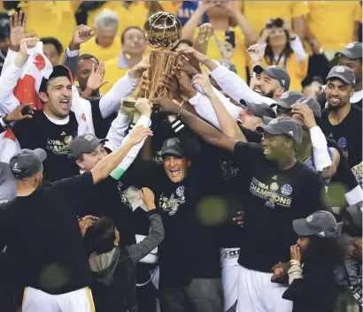  ?? RONALD MARTINEZ/GETTY IMAGES ?? The Golden State Warriors celebrate with the Larry O'Brien Championsh­ip Trophy after defeating the Cleveland Cavaliers 129-120 in Game 5 to win the NBA Finals at Oracle Arena on Monday in Oakland. NBA FINALS: WARRIORS 129, CAVALIERS 120