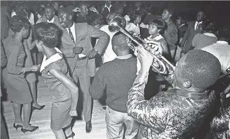  ?? ALABAMA DEPARTMENT OF ARCHIVES AND HISTORY ?? Trumpet player Bennie “Buckwheat” Payne of The Sheiks gets down with the audience at the Laicos Club in Montgomery, Ala. Circuit venues ranged from nighclubs to dance halls to dirt- floor juke joints.