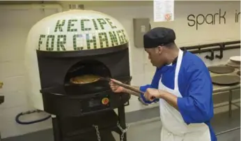  ?? TERESA CRAWFORD/THE ASSOCIATED PRESS ?? Inmate Marcus Clay pulls a hot, fresh pizza from the $16,000 oven at the Cook County Jail in Chicago.