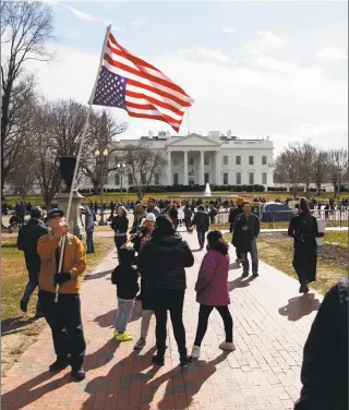  ?? Carolyn Kaster / Associated Press ?? A man walks with an American flag flying upside down during a protest on Monday in Lafayette Square in front of the White House in Washington to protest that President Donald Trump declared a national emergency along the southern border.