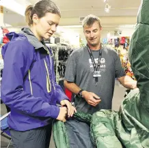  ??  ?? Bill Keeling helps Judith Boersma from the Netherland­s pick out a new sleeping bag at Wilson Mountain Sports in Lake Louise. Keeling said high end clothing and equipment have been in high demand all summer.