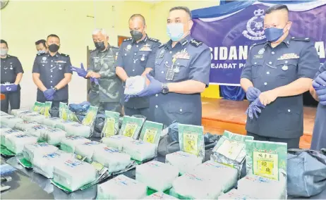  ?? — Photo by Chimon Upon ?? Aidi (second right) shows one of the drug-filled packages seized during the operation.