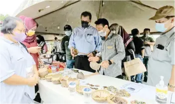  ?? — Photo courtesy of Edmund Samunting/Sabah Tourism Board ?? Datuk Joniston Bangkuai checking the handicraft­s made by Walai Ondoton Pitas Homestay community at Kampung Kuyuh in Pitas, on Friday.