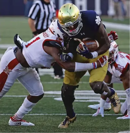  ??  ?? Notre Dame’s Josh Adams breaks away from De’Andre Montgomery of Miami ( Ohio) on Saturday. | JONATHAN DANIEL/ GETTY IMAGES