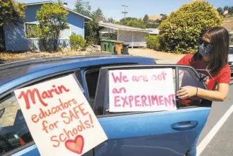  ?? Santiago Mejia / The Chronicle ?? Erin Frazier removes posters from her car after the teachers protested fully opening schools last week outside the Marin County Office of Education in San Rafael.