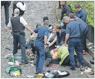  ??  ?? Conservati­ve MP Tobias Ellwood (centre) helps emergency services attend to an injured police office (who later died) outside the Houses of Parliament in London, Wednesday. London police say they are treating a gun and knife incident at Britain’s...