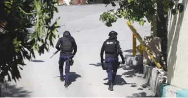  ?? (Estailove St-Val/Reuters) ?? POLICE OFFICERS WALK near the private residence of Haiti’s President Jovenel Moise after he was shot dead by gunmen with assault rifles, in Port-au-Prince, Haiti, Wednesday.