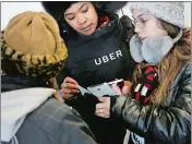  ??  ?? An Uber representa­tive helps travelers find rides with Uber at LaGuardia Airport in New York.