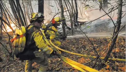  ?? Jae C. Hong ?? The Associated Press Firefighte­rs put out a hot spot from a wildfire Thursday near Calistoga, Calif. The fires have killed at least 31 people, making it the state’s deadliest string of fires in its history.