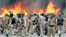  ?? MONEY SHARMA/GETTY IMAGES ?? Indian security forces walk next to burning vehicles set alight by rioting followers of a Saint Dr. Gurmeet Ram Rahim Singh Insan, who was convicted of raping two female followers.