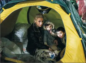  ?? ?? A woman sits with her children inside a tent.