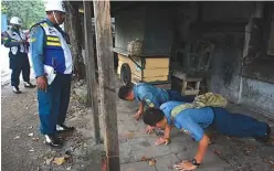  ?? MOCHAMAD SALSABYL/JAWA POS ?? JADI SEHAT: Dua anggota TNI-AL dihukum push-up karena melanggar peraturan lalu lintas di Jalan Kasuari kemarin.