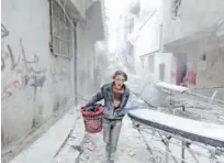  ?? File/ Reuters ?? A boy carries his belongings at a site hit by a barrel bomb in Aleppo.