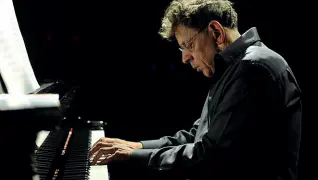  ??  ?? Note d’autore Sopra Philip Glass al piano. Nella foto sotto, il cantautore Gino Paoli