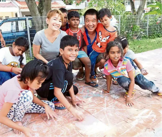  ??  ?? Liew (second from right, back row) and Chong (fifth from right, back row) organises outdoor activities like chalk drawing to encourage children to play outside. — Photos: ART CHEN/The Star