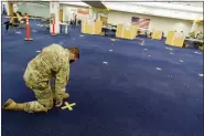  ?? DAVID GOLDMAN-ASSOCIATED PRESS FILE ?? Rhode Island Army National Guard Staff Sgt. Andrew Bates pulls up tape marking a line at a coronaviru­s massvaccin­ation site at the former Citizens Bank headquarte­rs in Cranston, R.I., June 10, 2021.