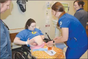  ?? (NWA Democrat-Gazette/Marc Hayot) ?? John Brown University nursing student Erin Pianalto wraps the ‘belly’ of Hannah Kintzel during the simulation.