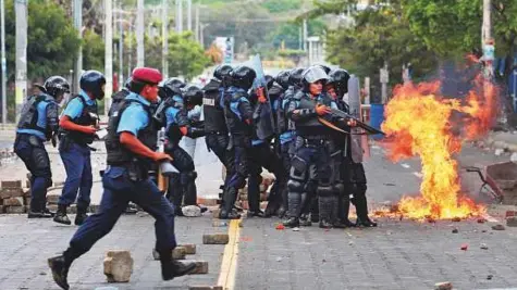  ?? Reuters ?? A petrol bomb explodes near riot policemen during clashes with university students protesting over a controvers­ial reform to the pension plans of the Nicaraguan Social Security Institute (INSS) in Managua, Nicaragua, on Friday.